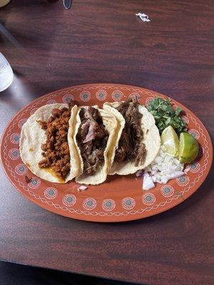 Three tacos with flour tortillas. Left to right Chorizo, Carnitas, Barbacoa