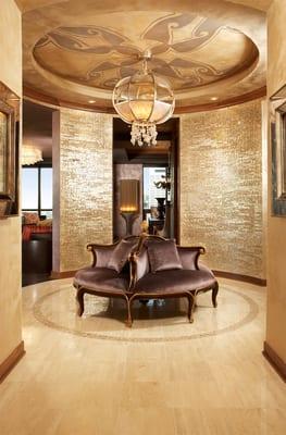 Mother of pearl wall covering provides luminescent backdrop for the grand chandelier and circular settee in penthouse foyer.