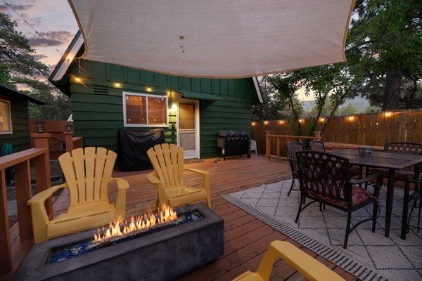 Backyard deck featuring a propane fire pit, barbecue grill with attached griddle & exterior dining table