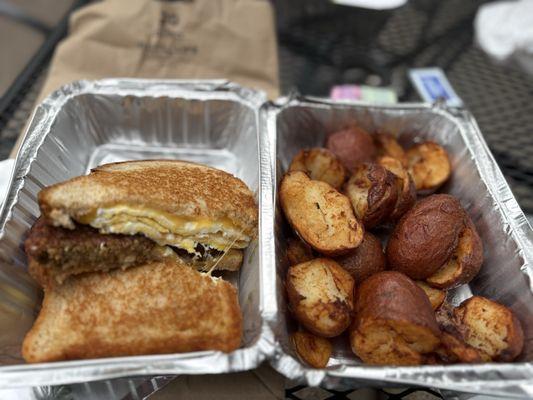 Breakfast sandwich with vegan sausage and a side of breakfast potatoes.