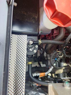 Radium oil catch can from GregRaceParts installed in a Lotus Emira.