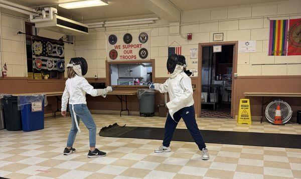 Kids fencing at the Santa Cruz Veterans Hall basement.