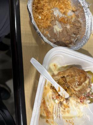 Half eaten chimichanga with rice and beans.