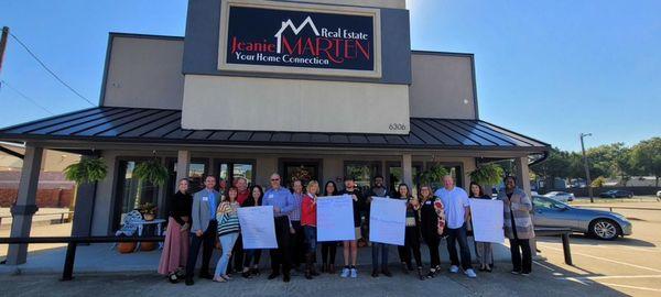 Real Estate agents showing off what they plan to do in the new year in front of the Jeanie Marten Real Estate office building