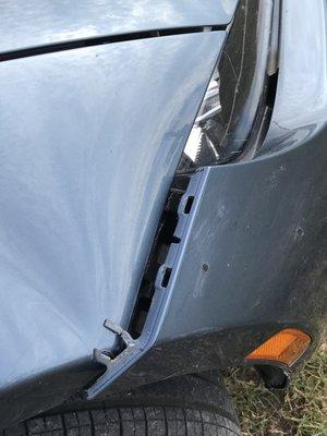 Broken Bumper bracket and folds in right fender Caused by Wrecker!  $1000 estimate to fix.