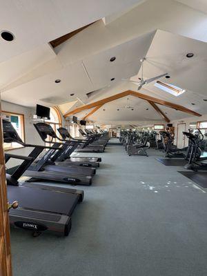 Cardio room upstairs featuring treadmills, bikes, and elliptical