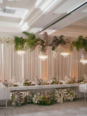 head table scape with stunning florals, chandeliers & candles