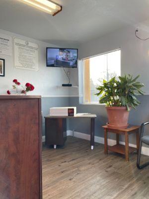 Cute waiting room with a coffee maker, a tv, chairs, and some plants!