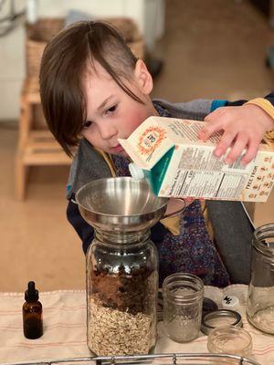 A Kindergarten age child, preparing overnight oats for the classroom