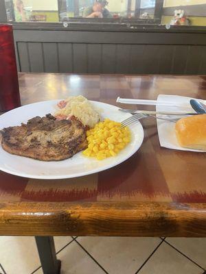 Pork chop sauerkraut and sausage and corn and a roll.