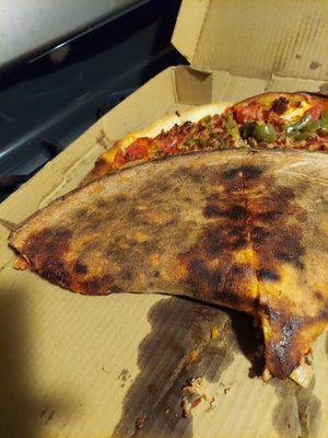 The burnt bottom of a Supreme pizza.