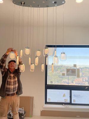 Chris Wayne installing a chandelier