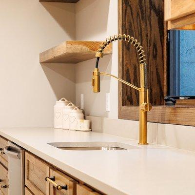 Modern kitchen plumbing installation featuring a stylish gold pull-down spout faucet.