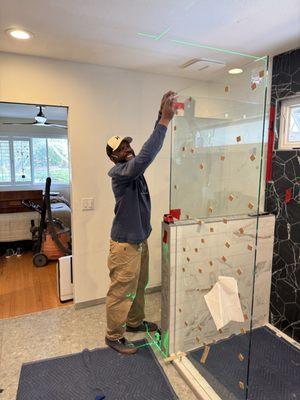 Tarnell installing a swing door shower glass.