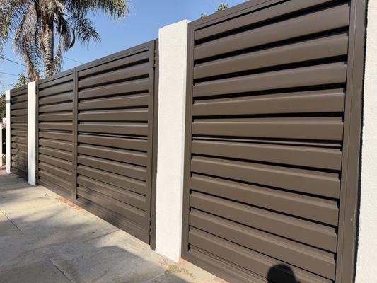 A modern metal fence provides complete privacy at an affordable price, featuring a powder-coated bronze finish. EAGLE ROCK CALIFORNIA