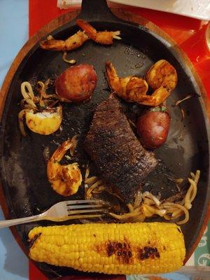 Grilled Steak and Shrimp served with onions, potatoes and Corn on the Cob and a separate side of Rice. Beans and veggies.