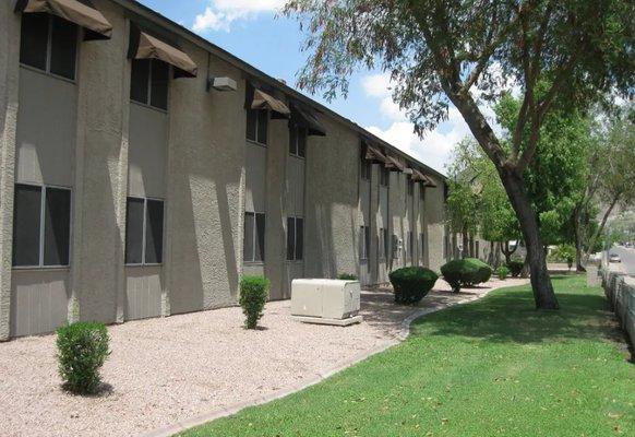 A long building with a lot of windows and bushes in front.