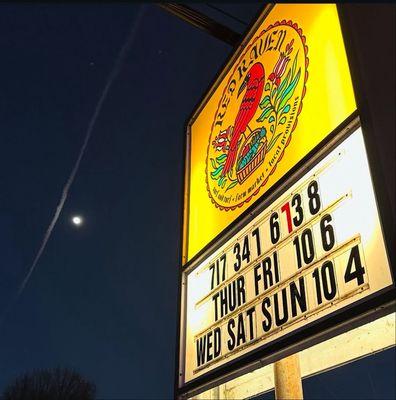 Street Sign with phone number and store hours.