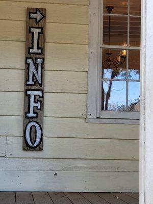 Sign on house with arrow pointing to half-empty rack of brochures.