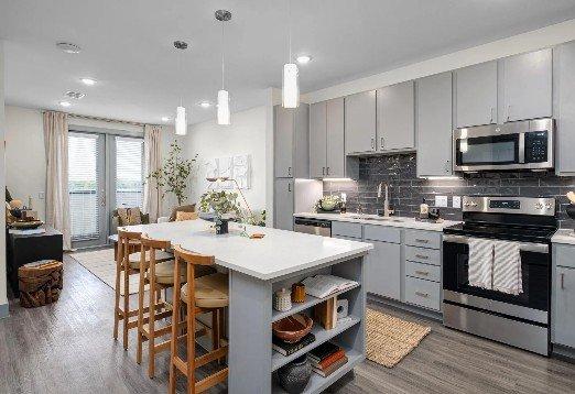 thoughtfully designed kitchen features contemporary gray cabinetry, stainless steel appliances, and a spacious island with ba...