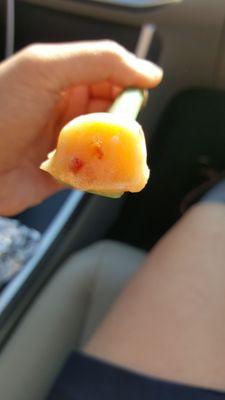 Scoop of peach with specks of peaches and peach skin.