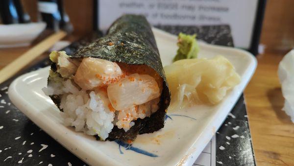 Spicy scallop hand roll with avocado and tabiko.