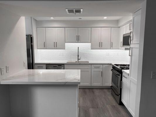 Factory Cabinets Kitchen Remodel | White shaker door and drawer style and quartz countertop. Wavy subway tile backsplash.