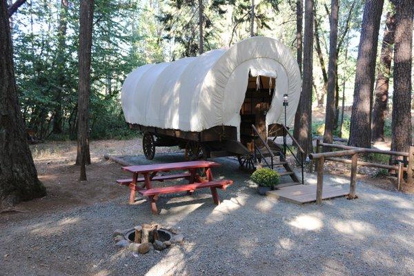 Outside one of our two rentable wagons featuring a king sized bed, twin bunkbed, heat, outlets, lights, fire-pit and charcoal grill.
