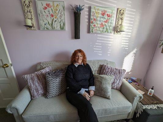 Laura Demougin, licensed therapist at New Blooms Wellness in Franklin, Indiana, sitting on the couch in her office.