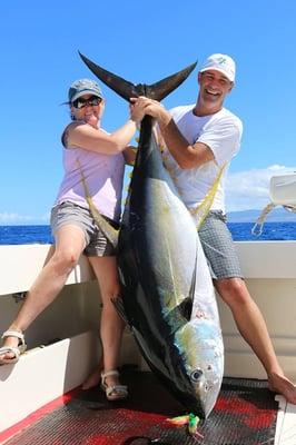 Happy customers holding up a big Yellowfin Tuna