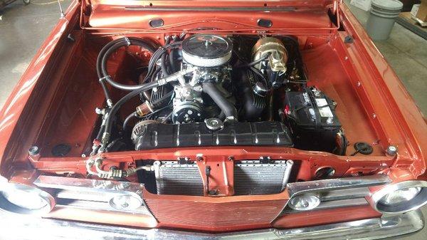 Under hood of a1965 Barracuda. A/C, power disc brakes and an electric cooling fan have been added . The vehicle was also rewired.