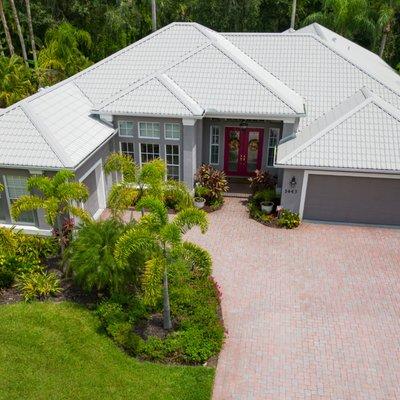 Front-facing photo of a tile-roofed home surrounded by palm trees, showcasing roofing services in Bradenton by Noland's Roofi...