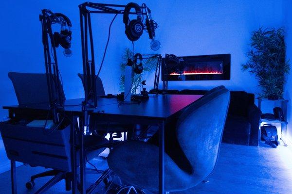 Podcast studio with four connections, extra available by request. Control room is separated by a wall and window. Video recording available
