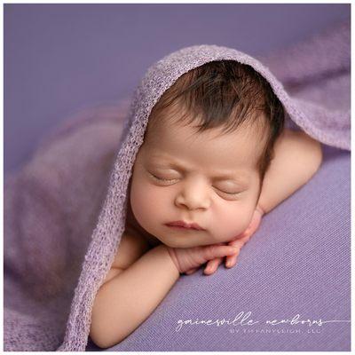 Newborn Baby Photos. Infant on purple blanket.