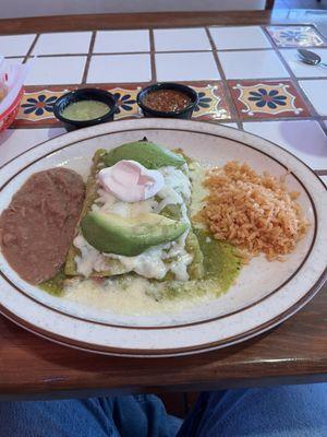 Enchiladas Laura , chicken and green sauce with sliced avocado on top , rice and refried beans