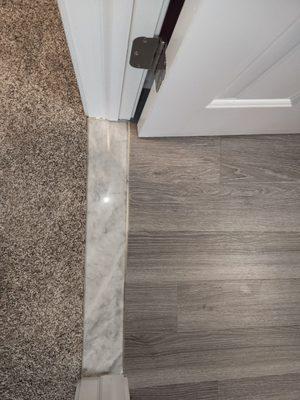 poorly cut flooring. They didn't bother to remove any of the thresholds or trim before installing the flooring