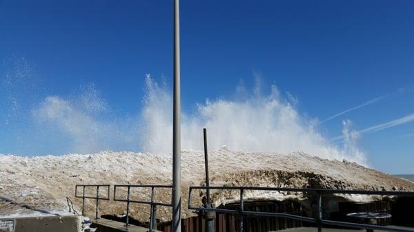Waves crashing over the ice buildup at the end of the pier.