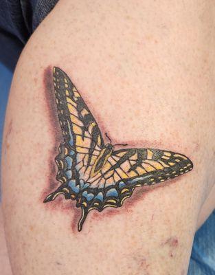 Yellow butterfly tattoo in memory of my Mother with a blue heart hidden in the design in memory of my grandson.