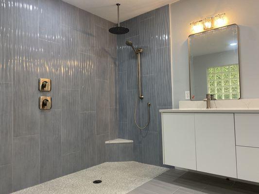 Bathroom shower remodel complete with rain shower head and handheld sprayer.