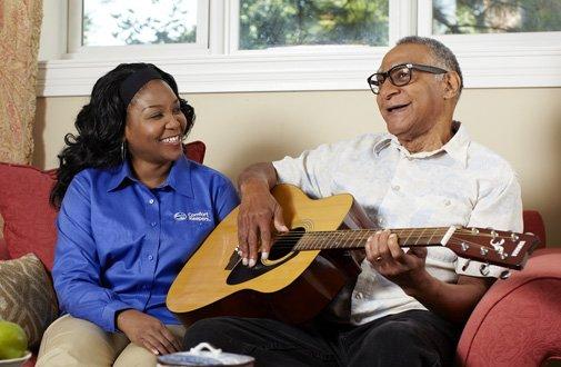 Client playing the guitar with his caregiver
