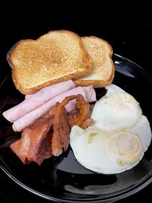 Desayuno con huevos, tostada, jamón y bacon