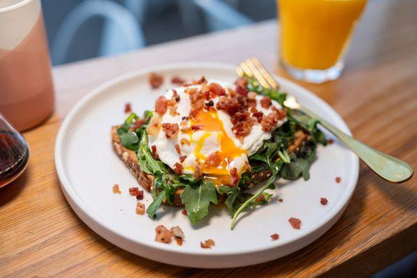 Avocado Toast: Fresh & perfectly balanced--multigrain toast topped with egg, bacon bits, avocado & arugula in our signature vinaigrette.