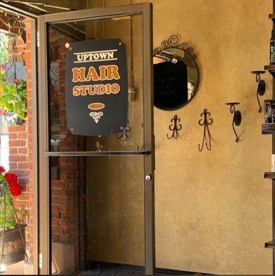 The front door with the sign for Uptown Hair Studio