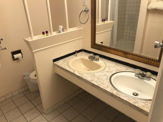 Mis-matched sinks balanced by the dingy environs of the bathroom