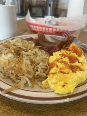 Scrambled eggs, hash browns, bacon, biscuit and coffee