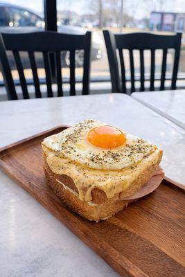 Croque Madame: Buttery Michelin-style brioche layered with savory ham, melted gouda cheese, our house smoked-cheese mayo