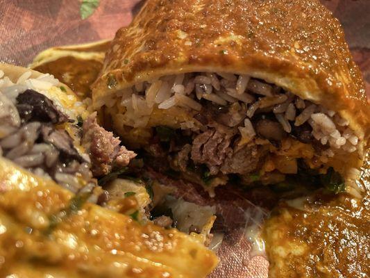 Smothered burrito close up: added onions and peppers, protein is steak.