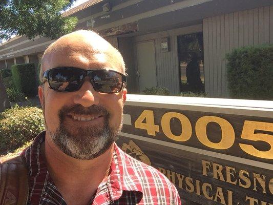 Chris by the sign for the business on Fresno Street
