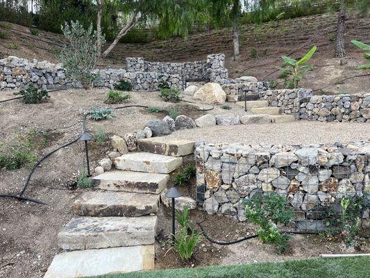 Gabion wall with stone pathways accessing slope in Thousand Oaks backyard.