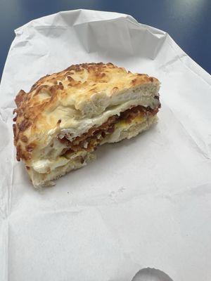 Half of a Breakfast Bagel, made with bacon, egg, provolone, and cream cheese on a Asiago bagel.